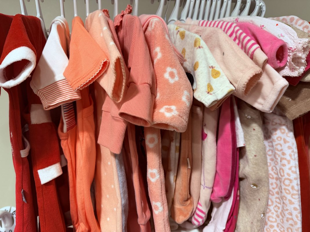 Vêtements enfants d’occasion rangés sur cintres dans une boutique de seconde main